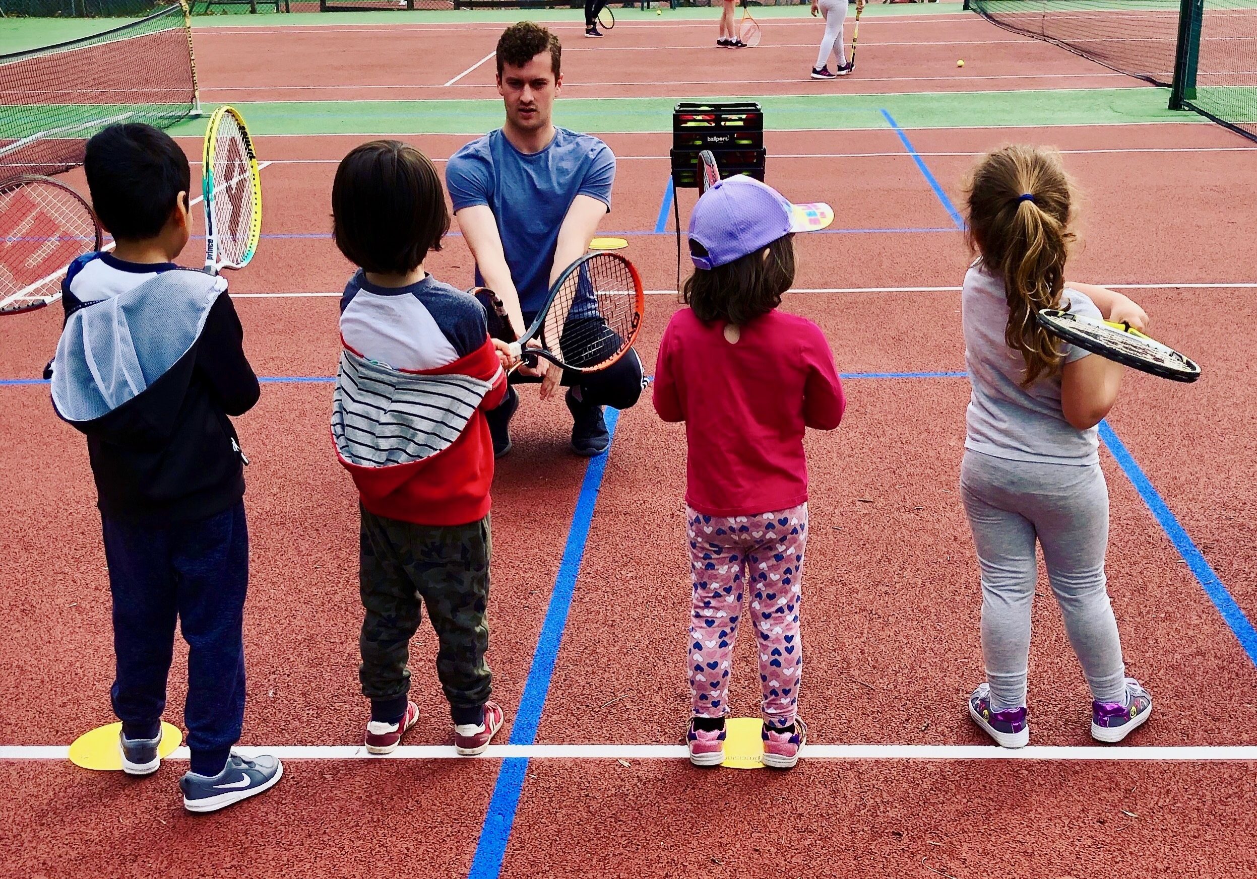 Our tennis coaches helping mini tennis children